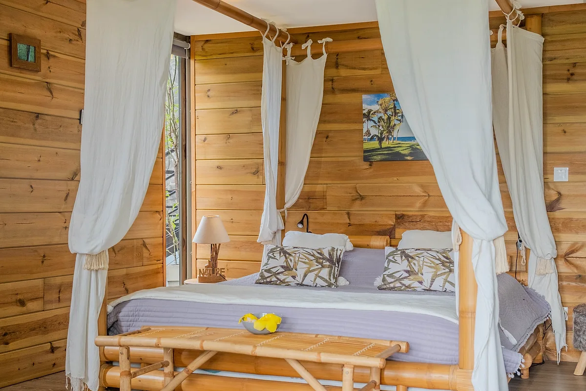 Le lit à baldaquin du bungalow Combava, dans un intérieur en bois