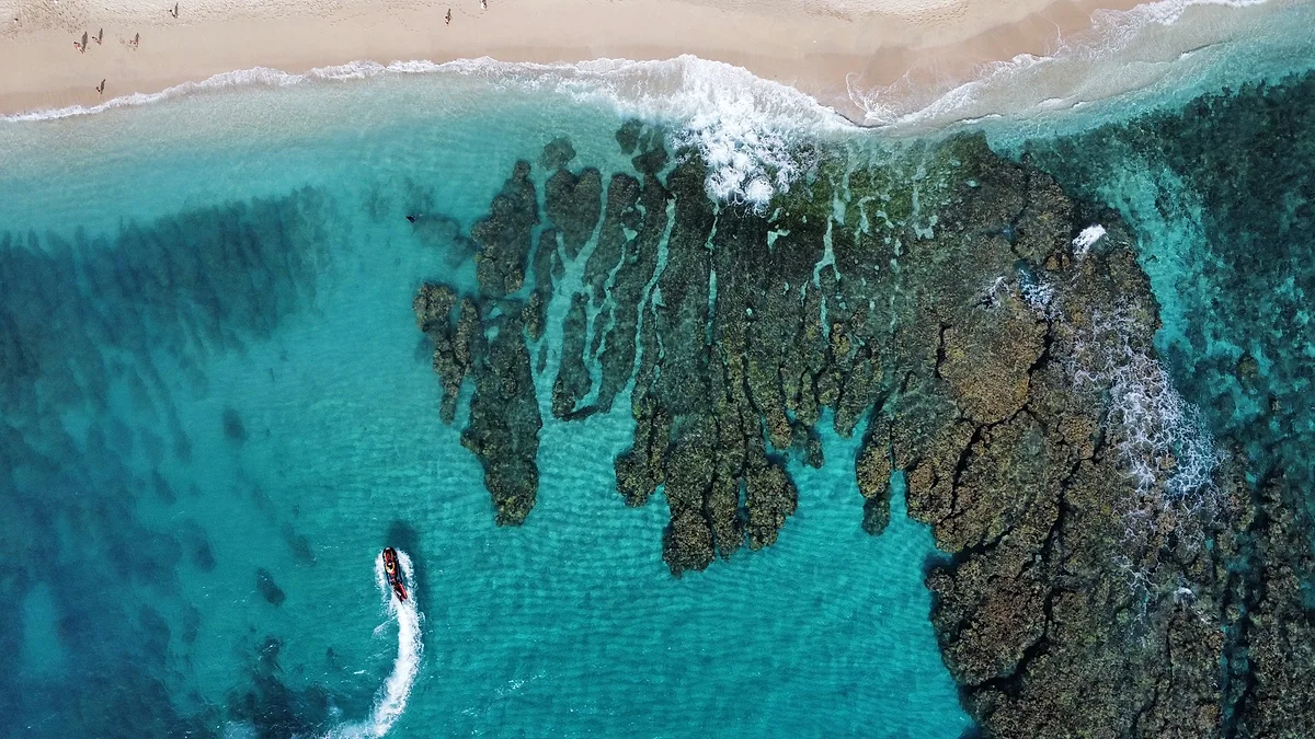 Une côte de l'île vue du ciel, entre roches noires et eau turquoise