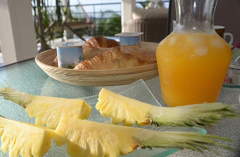 Un petit déjeuner avec ananas, croissants et jus d'orange