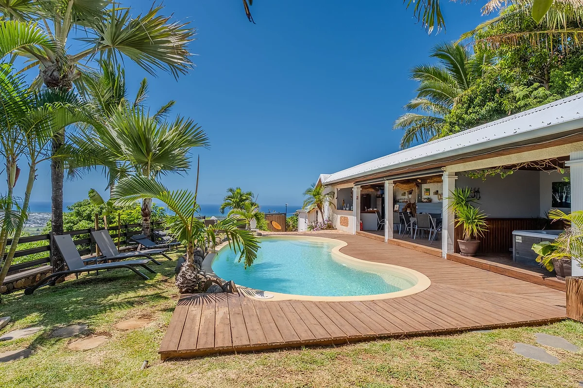 La piscine et sa terrasse en bois, avec le pool house