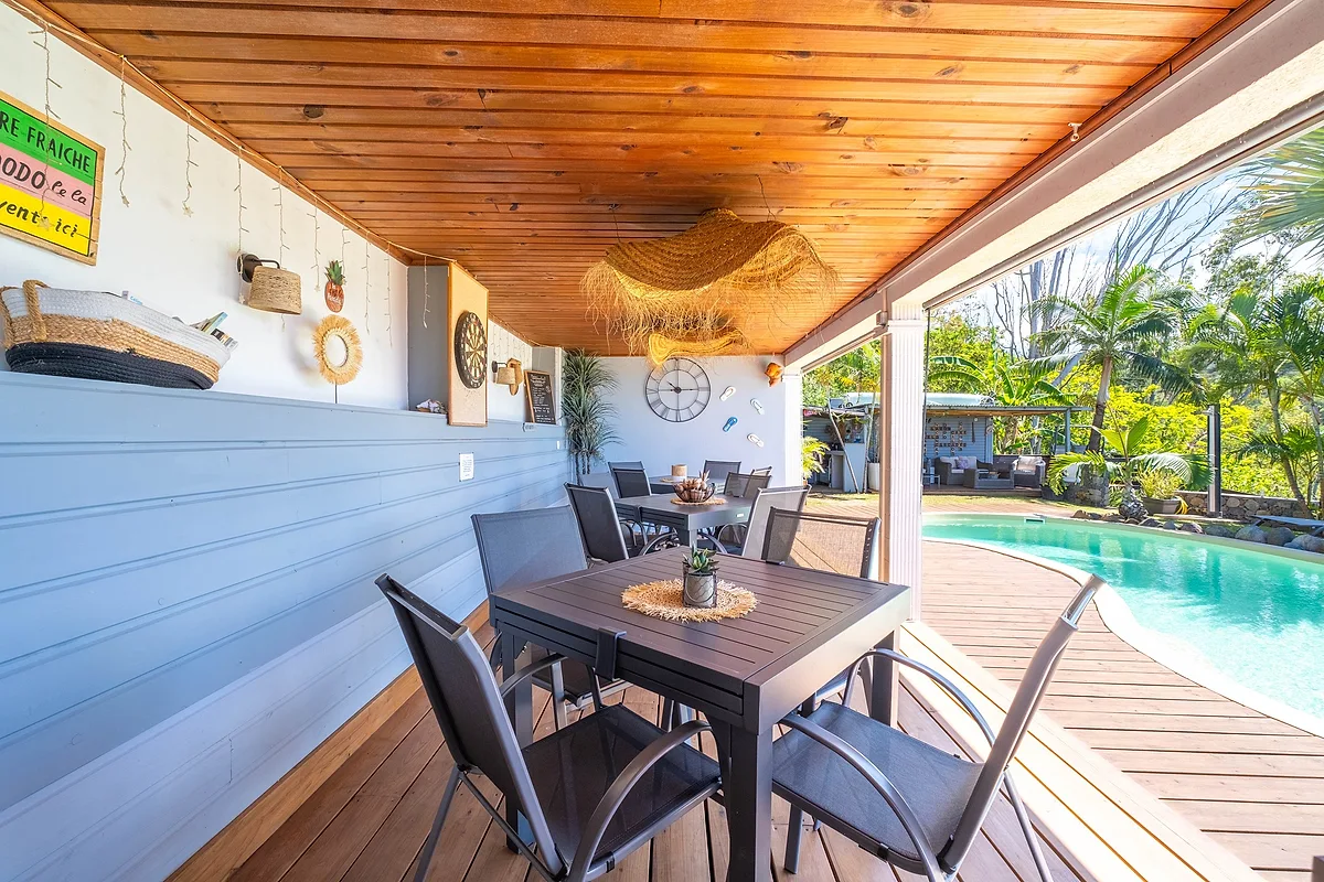 Une table dressée au bord de la piscine, sous l'abri en bois